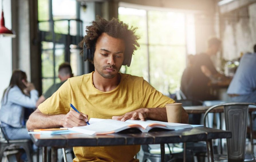Man at a cafe writing in a book and working on his brand story