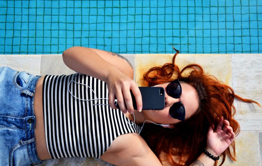 woman sitting on phone by the pool