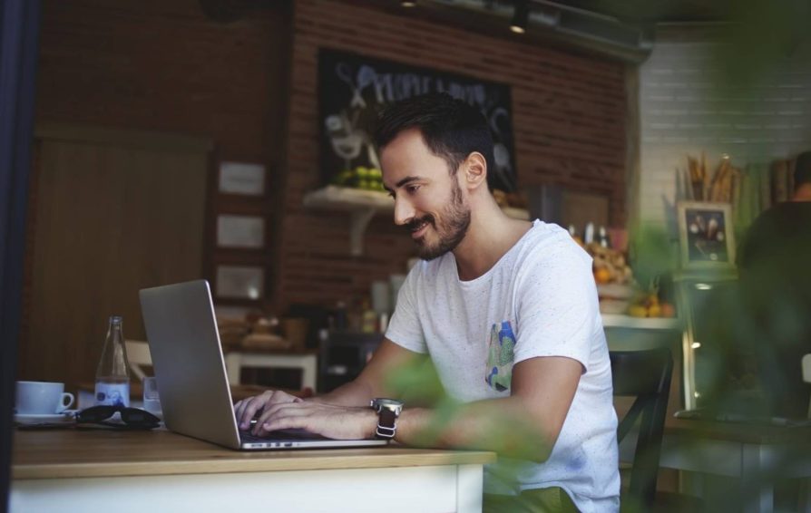 Man sitting in coffee shop at a table using his laptop