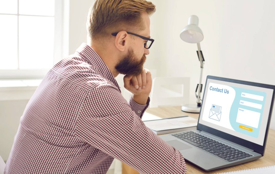 Man looking at laptop with contact form examples