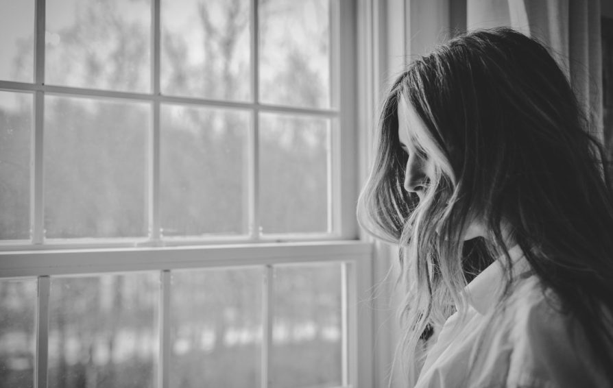 Black and White Image of Woman Looking Out Window