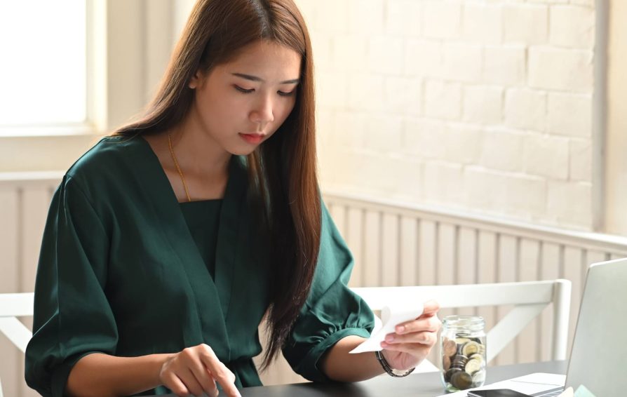 Woman calculating finances using an expense report example