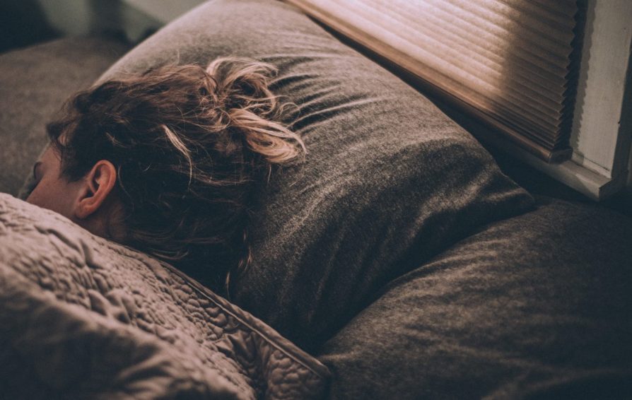 a woman resting in bed near a window
