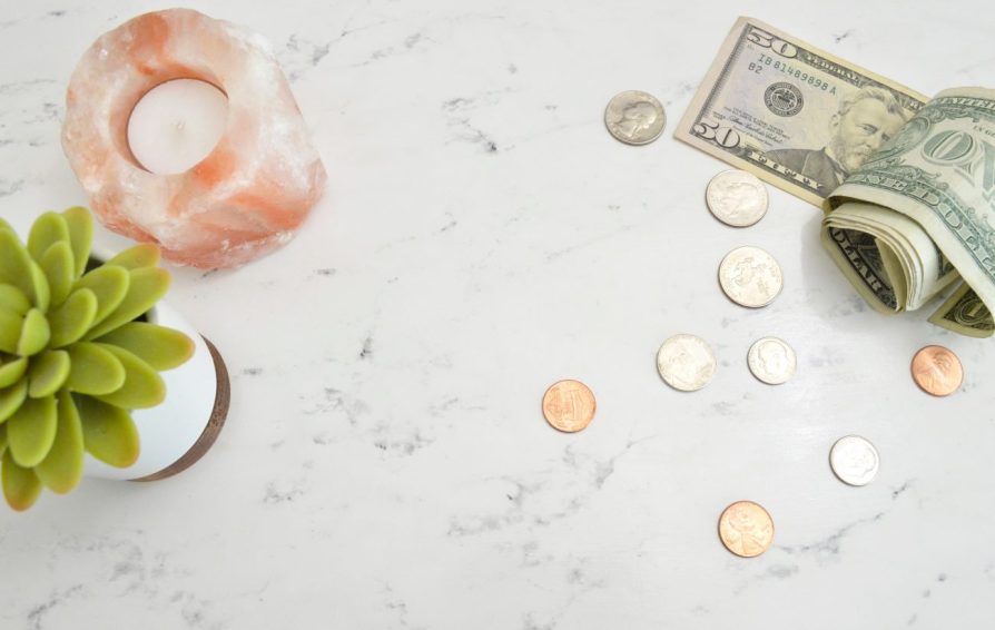 money on a table with a plant and a candle