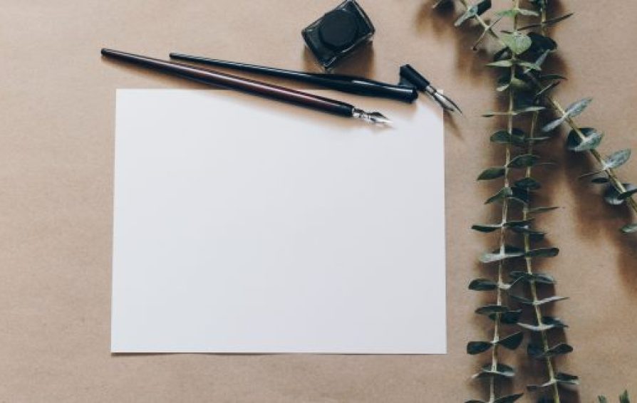 a blank piece of paper on a desk with a pen