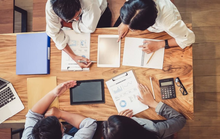 Group of workers at a table below mapping their clientflow with various documents