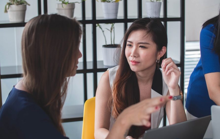 two women sitting at a desk with a laptop talking about small business goal setting