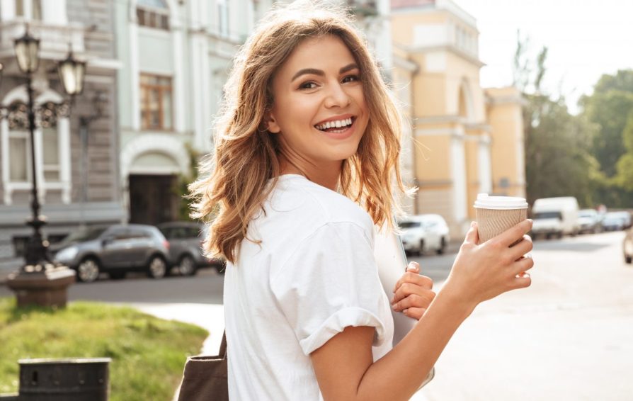 woman walking down the street with a coffee cup