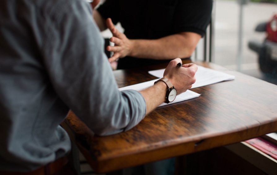 Close up of two men working at a wooden desk