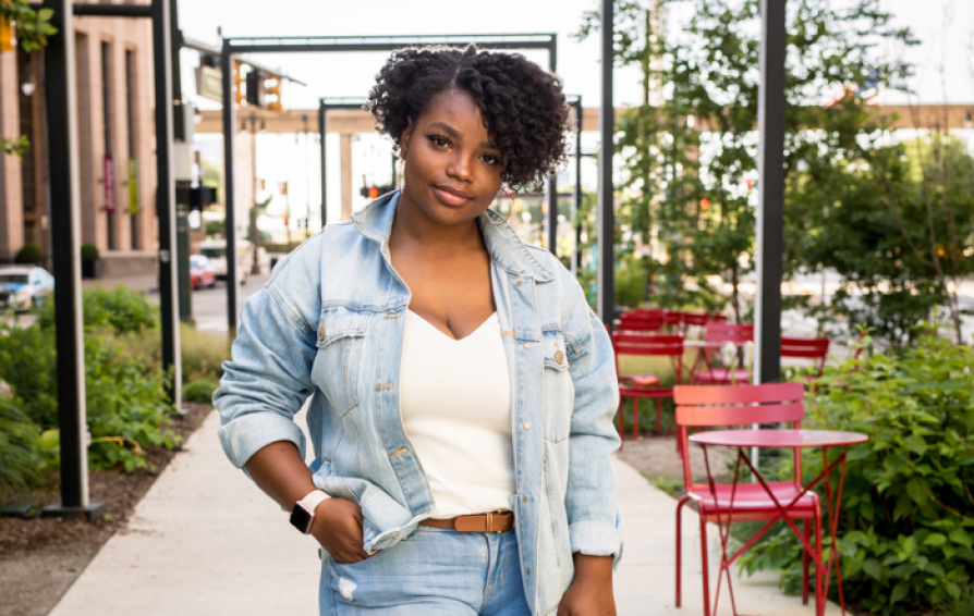Woman wearing a jean jacket with one hand on hip.