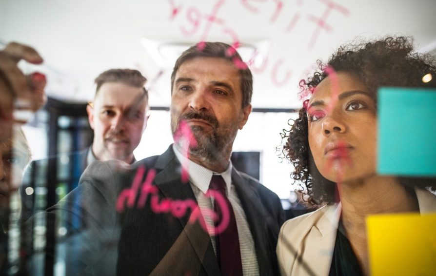 a group of people writing on a whiteboard learning How to Create a Simple 5-Point Business Plan