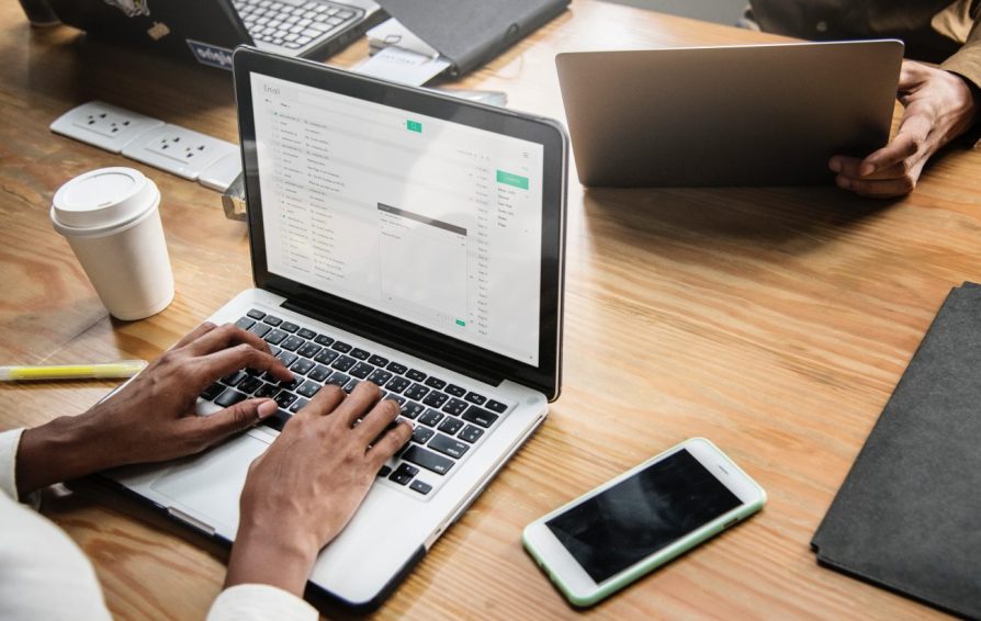 laptops on a desk with people working at them