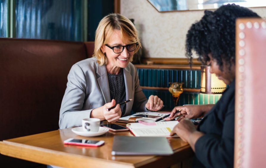 Woman in a business suite works on paper work with a client.