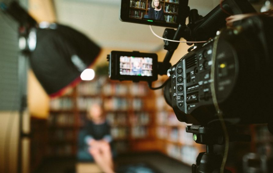 a video camera filming a woman in an office setting
