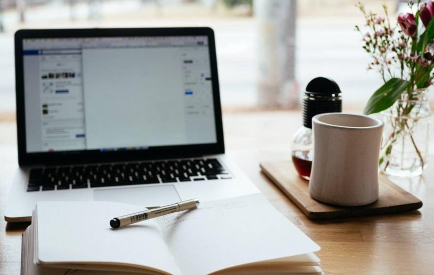 Journal on a desk with laptop open in the background