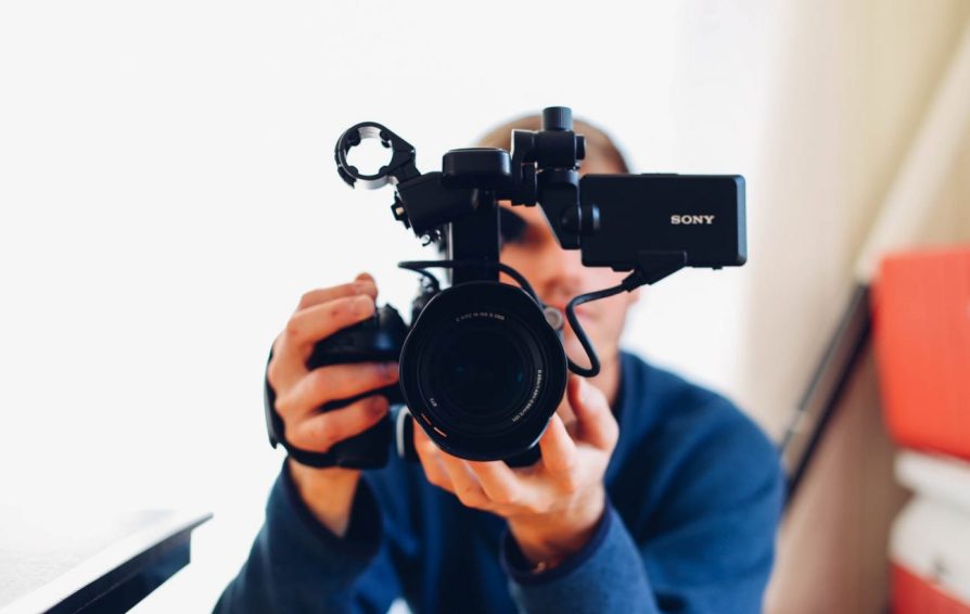 Man looking through video camera lens.