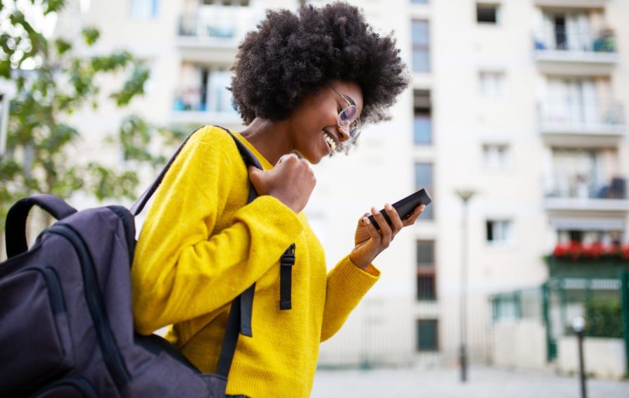 woman walking down the street looking at her phone