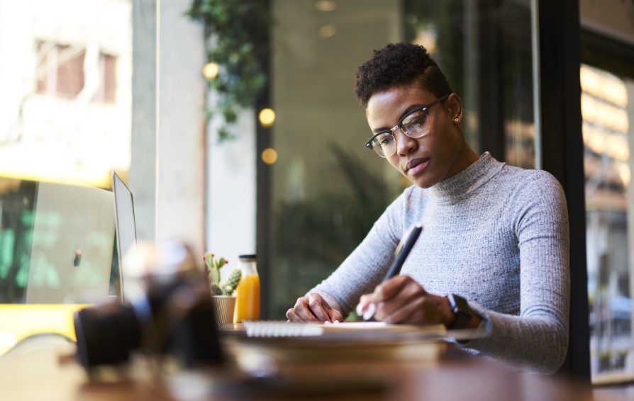 A woman in glasses works at a table