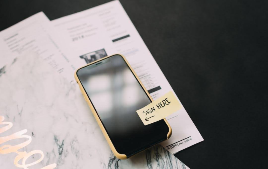 an iphone with a post-it note saying 'sign here'