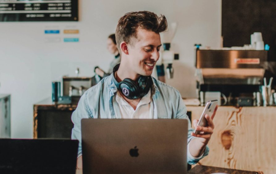 Man using small business software on his phone and laptop