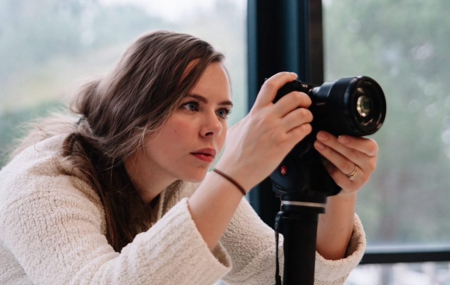 A woman adjusts a DSLR camera on a stand