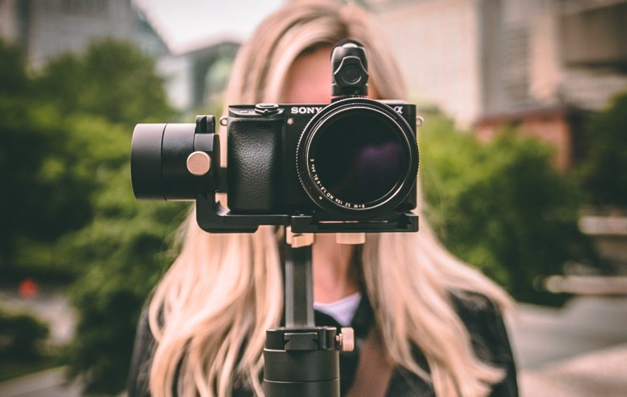 photographer holding a camera up covering her face