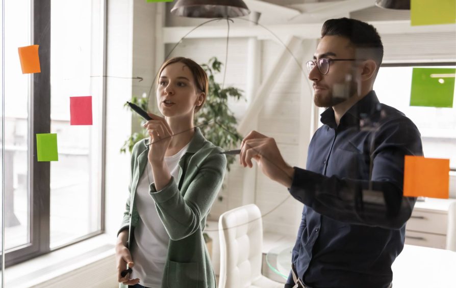 A man and a woman working through workflow examples on sticky notes