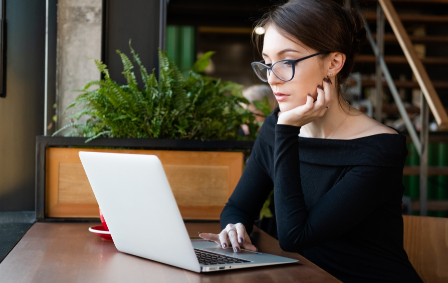 Woman thinking at her computer as she writes an email.
