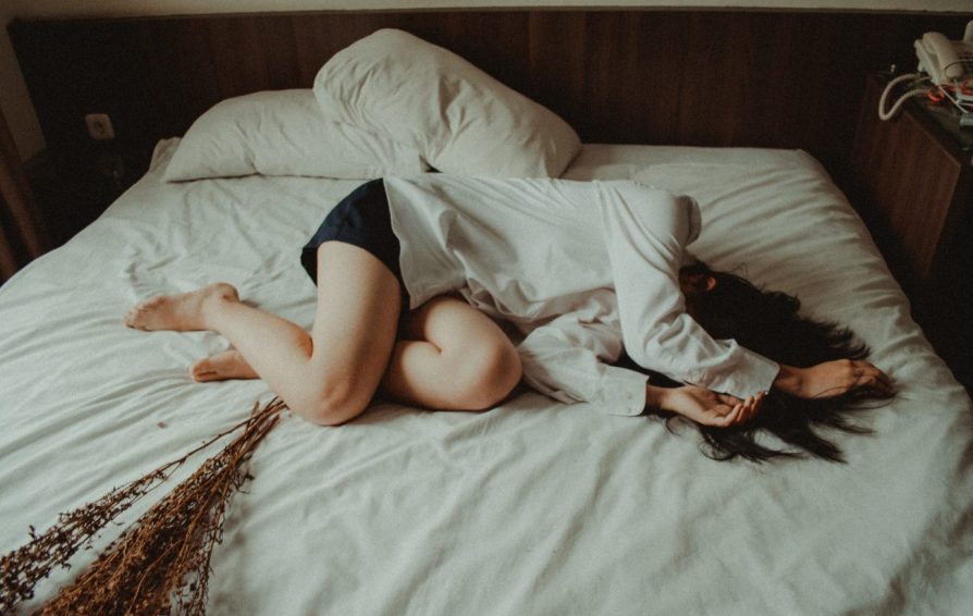 woman laying on a bed with dried flowers