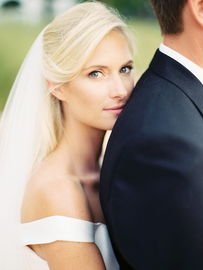 Close up of a bride looking at the camera as she leans on the groom.