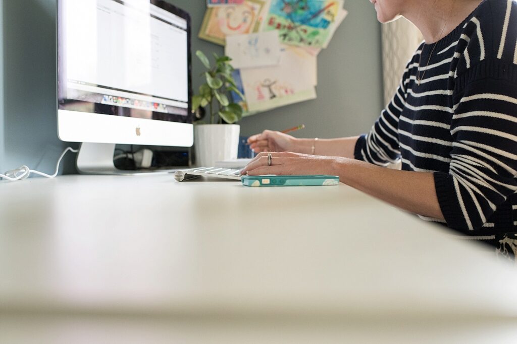 A woman works at a desk on an iMac.
