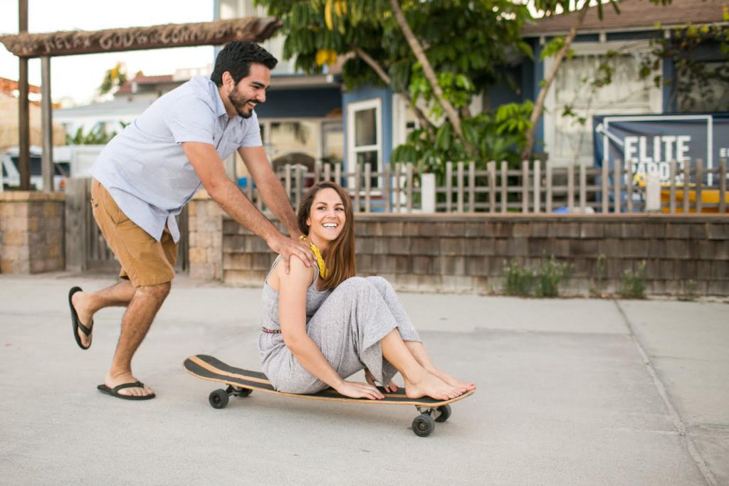 Man pushing woman on a skateboard.