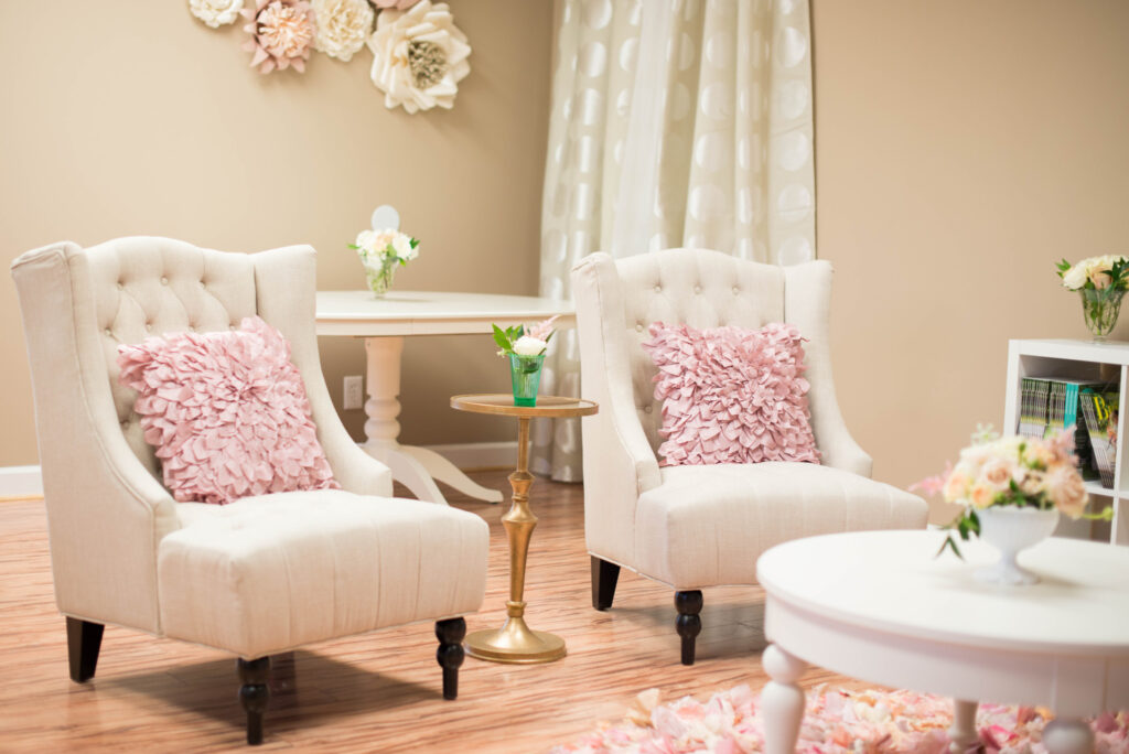 Two white chairs with pink, petal accent cushions in a stylish and feminine living room