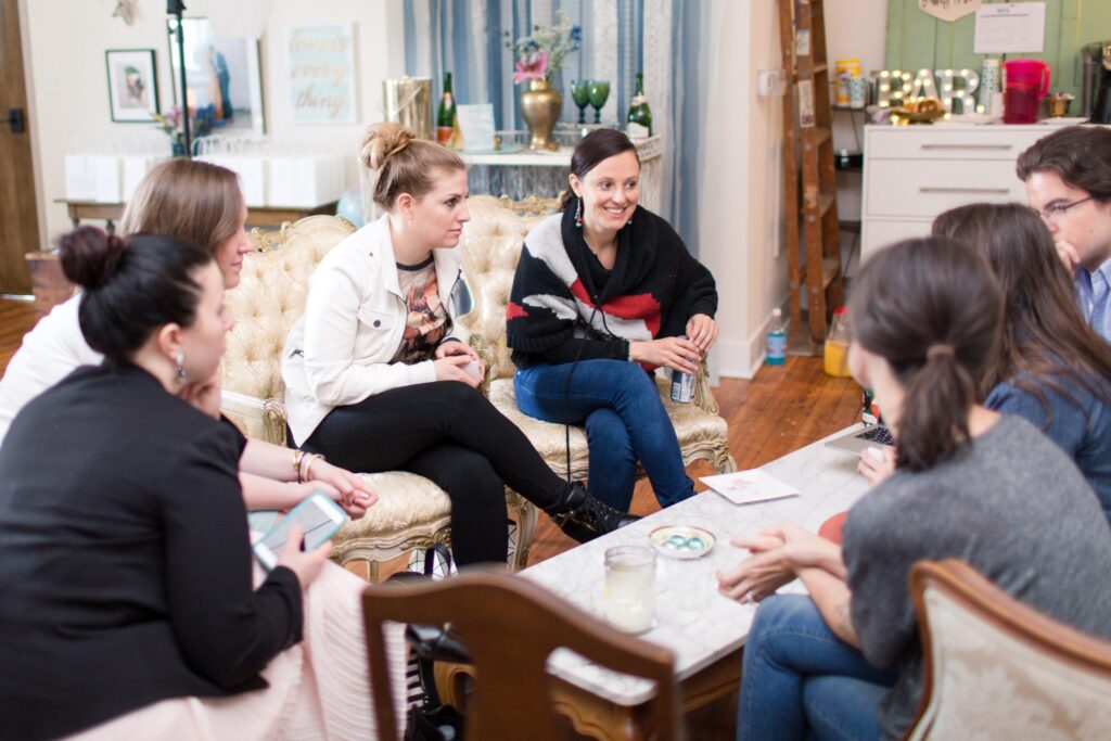A group of people sit around a coffee table, engaged in conversation.