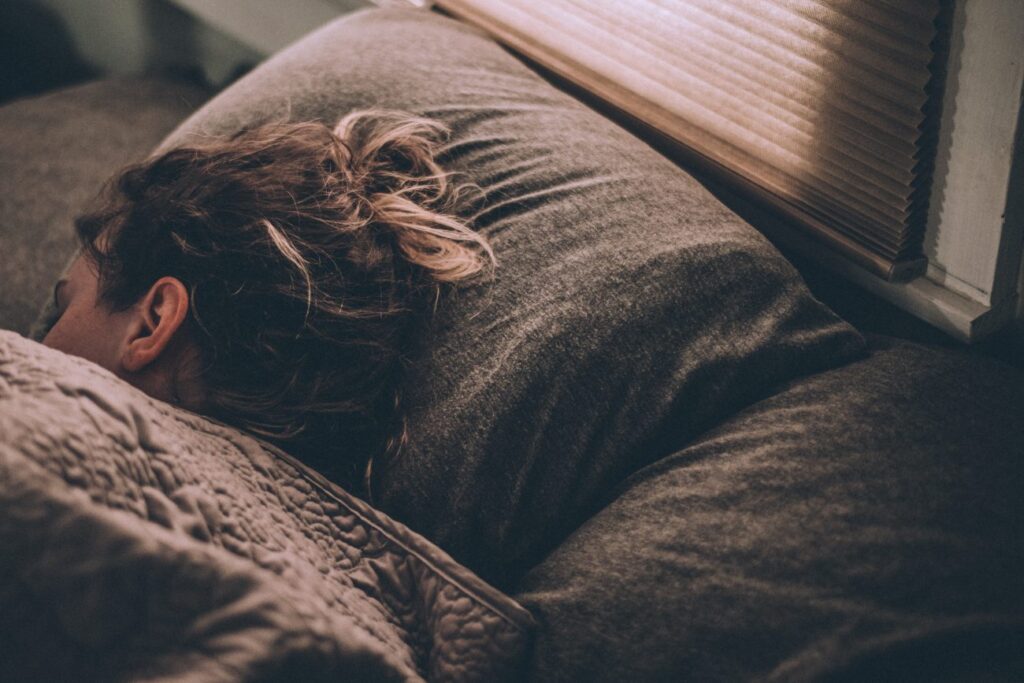 a woman resting in bed near a window