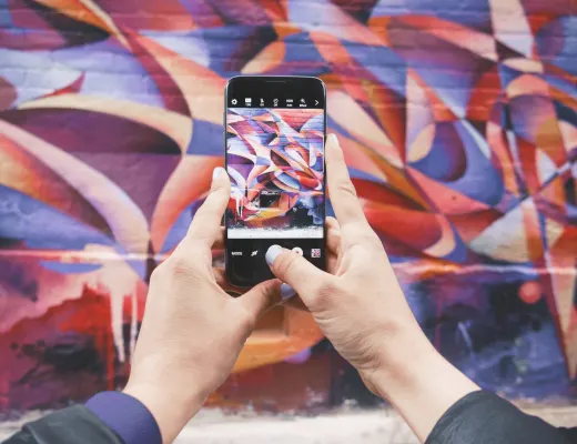 holding up a camera in front of a colorful mural to create a perfect pinterest pin