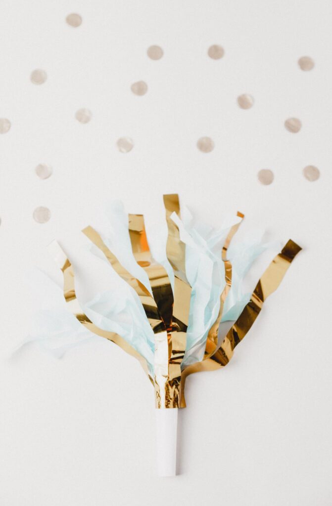 A gold and teal party streamer on a polka dotted background