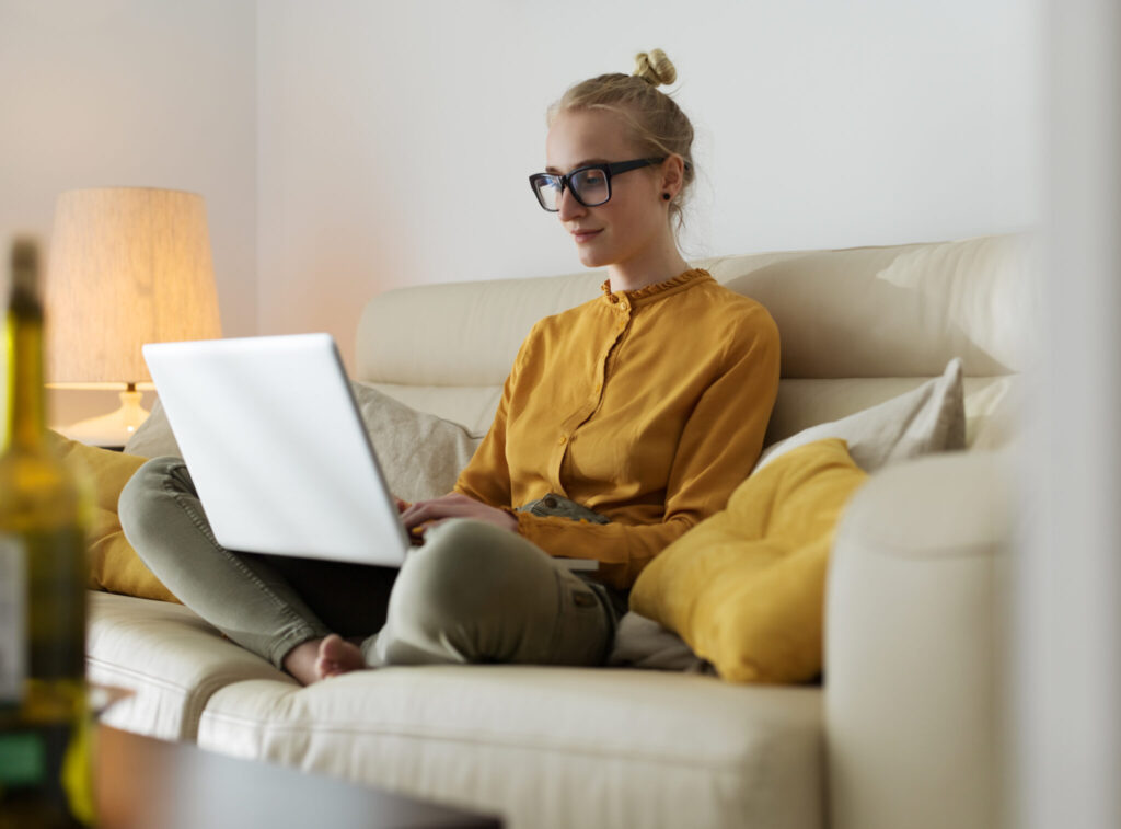 Woman working on computer while lounging on couch.
