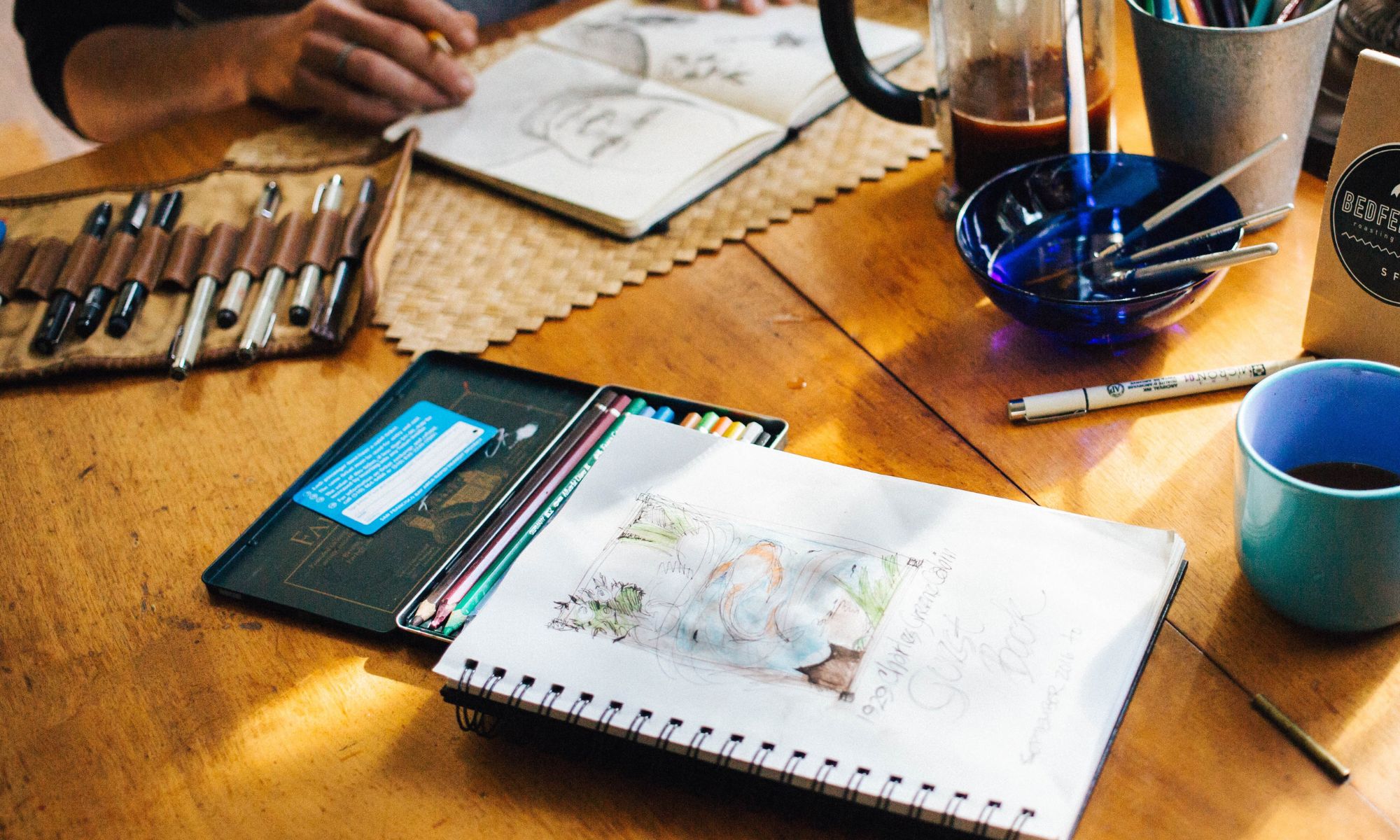 Creative artist sketches and paints watercolors while drinking coffee.