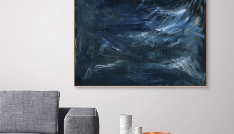 a living room scene with a grey couch, an accent table and a large painting
