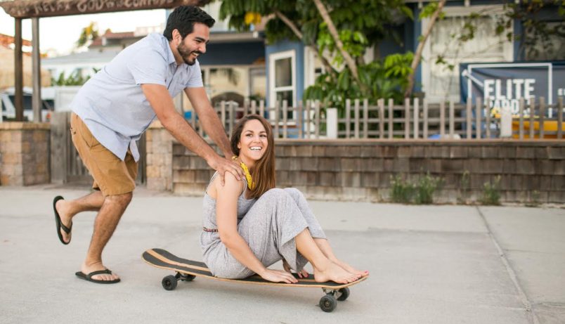 Man pushing woman on a skateboard.
